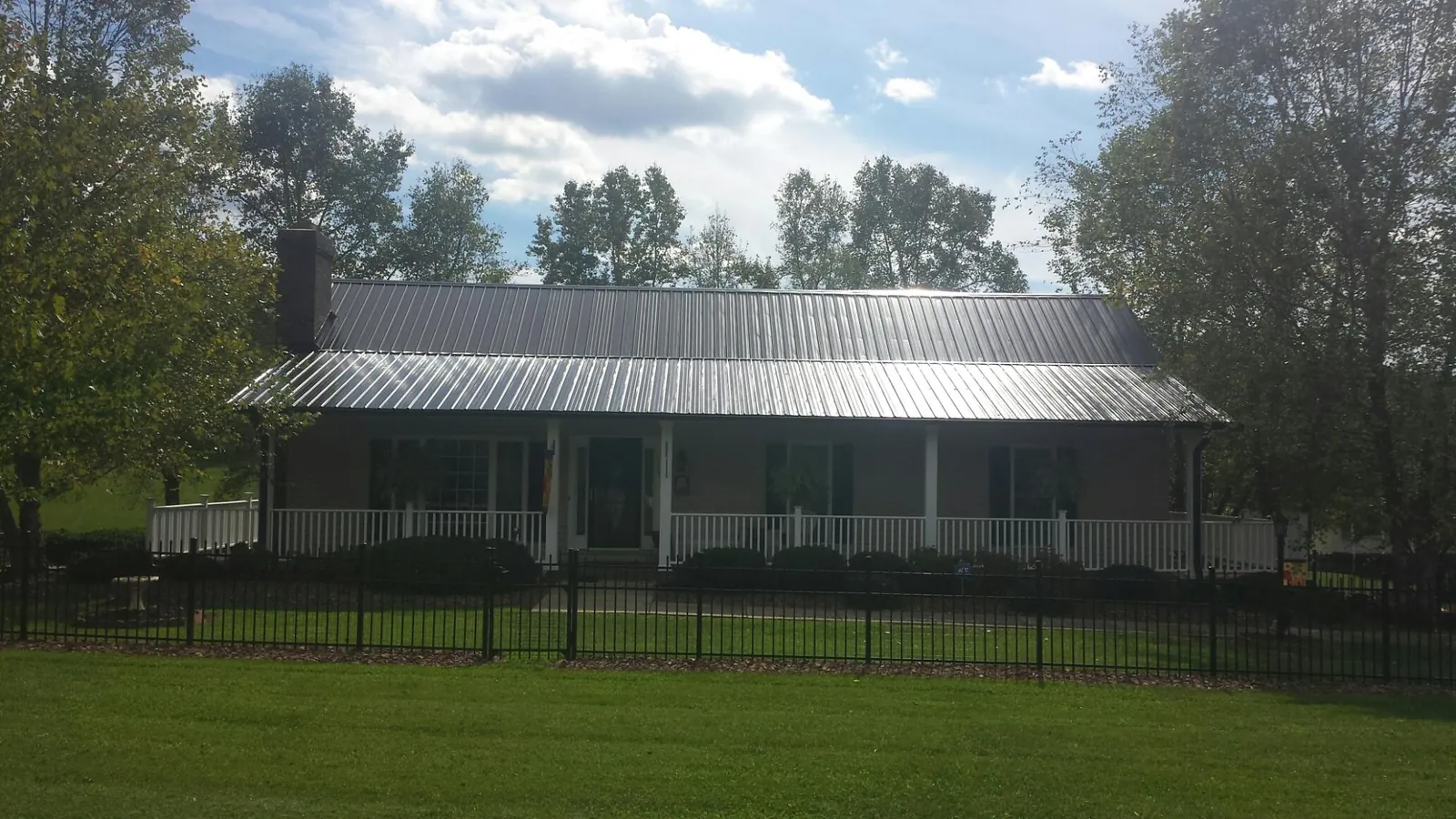 Gray metal roof on a brick ranch with a full width front porch — Gutter Guard Installation work by our crew in Oakley